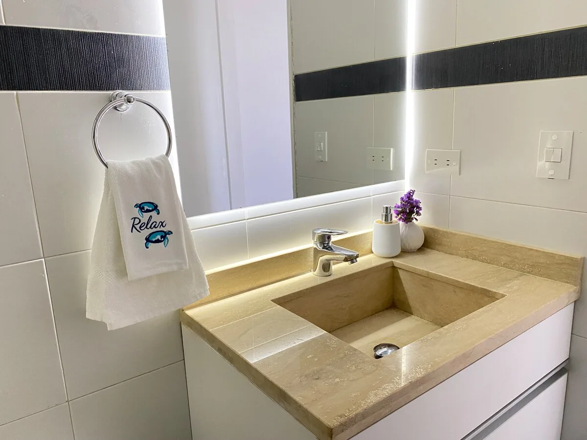 Baño completo con lavabo de piedra y espejo iluminado