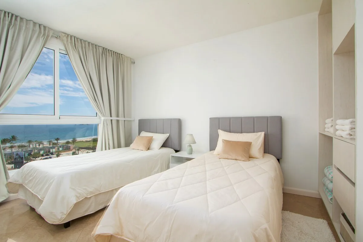 Segundo dormitorio con dos camas individuales y ventana al mar